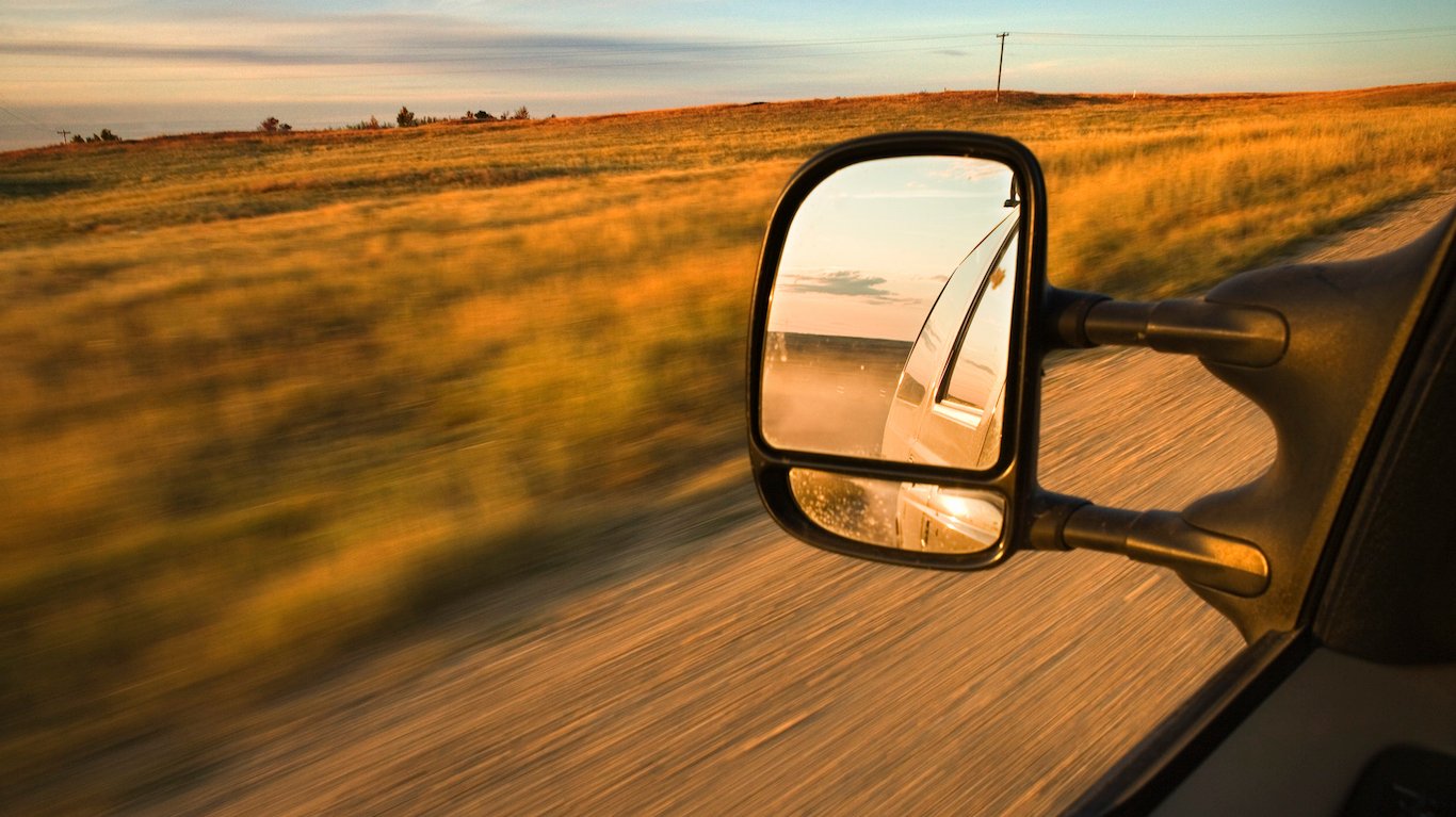 Mirror of car driving through rural fields, North Dakota
