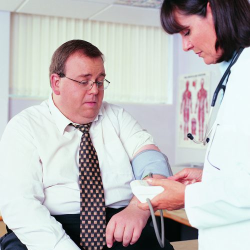 Overweight Businessman Having his Blood Pressure Taken by a Doctor