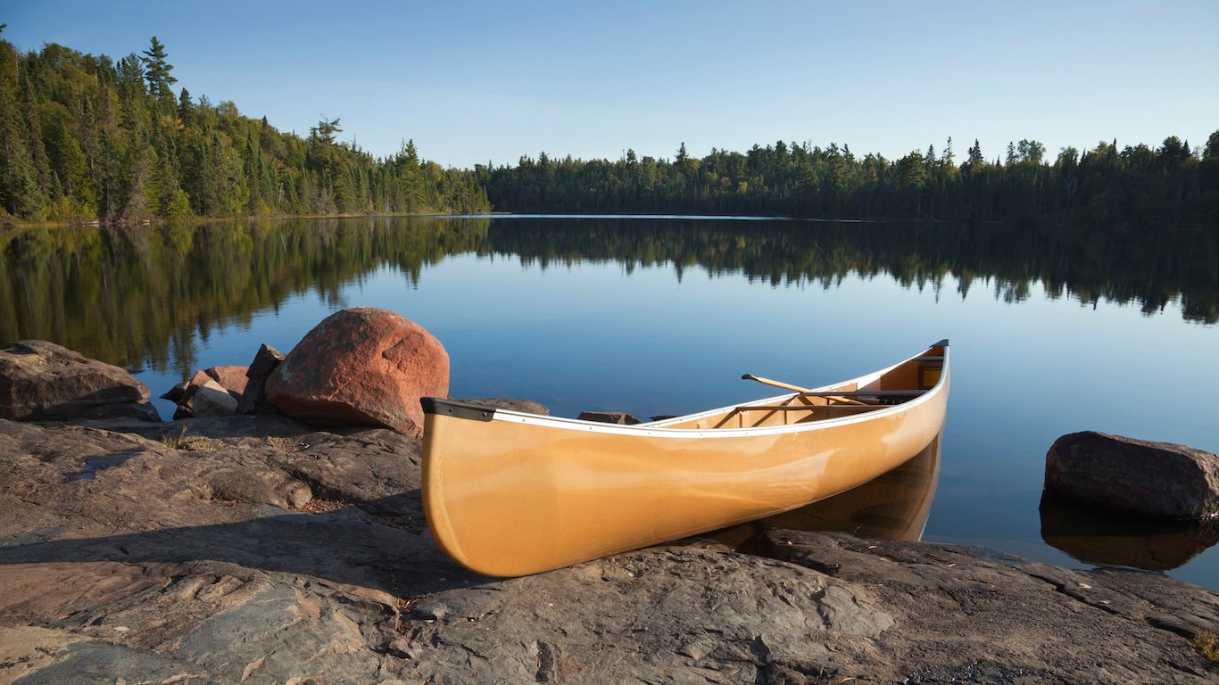 A yellow canoe rests on a rocky shore of a calm blue lake in the Boundary Waters of Minnesota