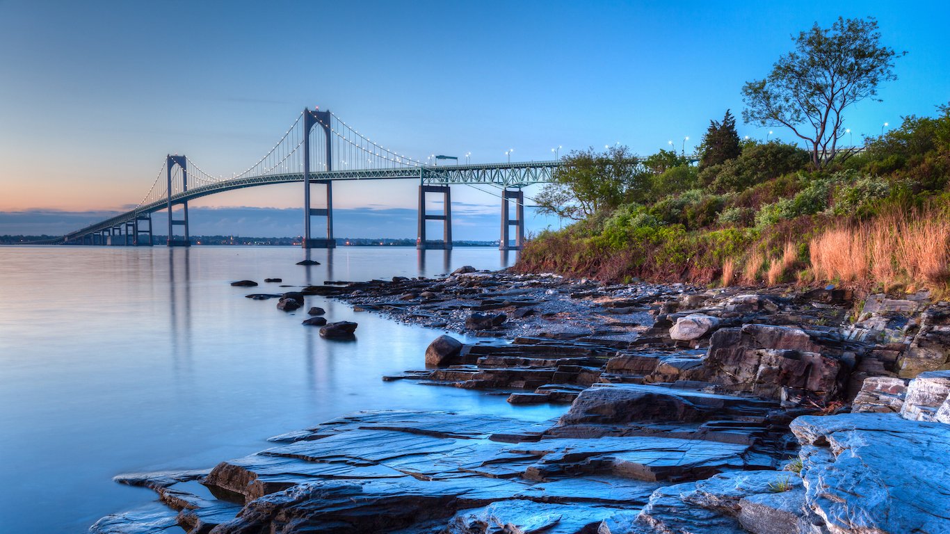 This is a long exposure HDR of the illuminated Newport bridge from Taylor's Point near Jamestown, Rhode Island, USA. It was taken at sunrise with a rocky seascape in the foreground.