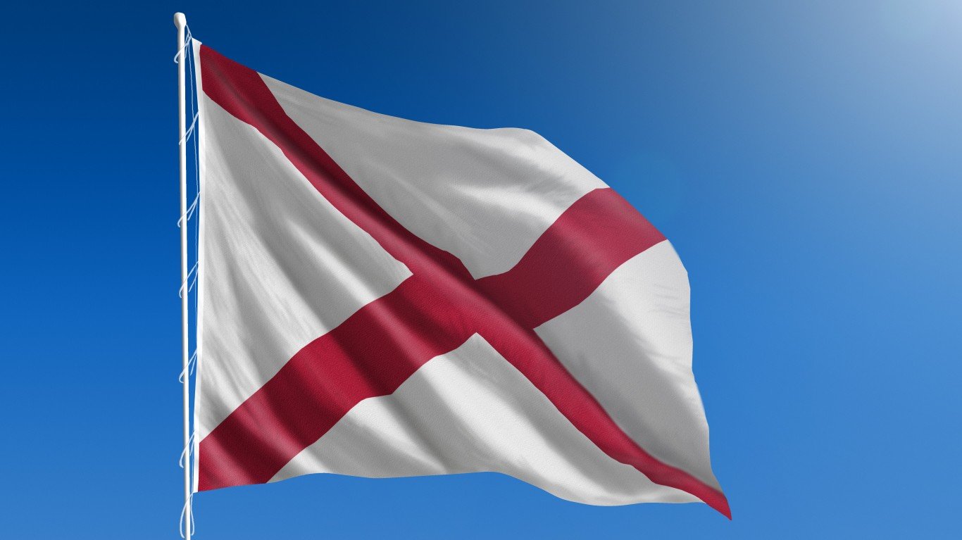 The flag of the state of Alabama blowing in the wind in front of a clear blue sky