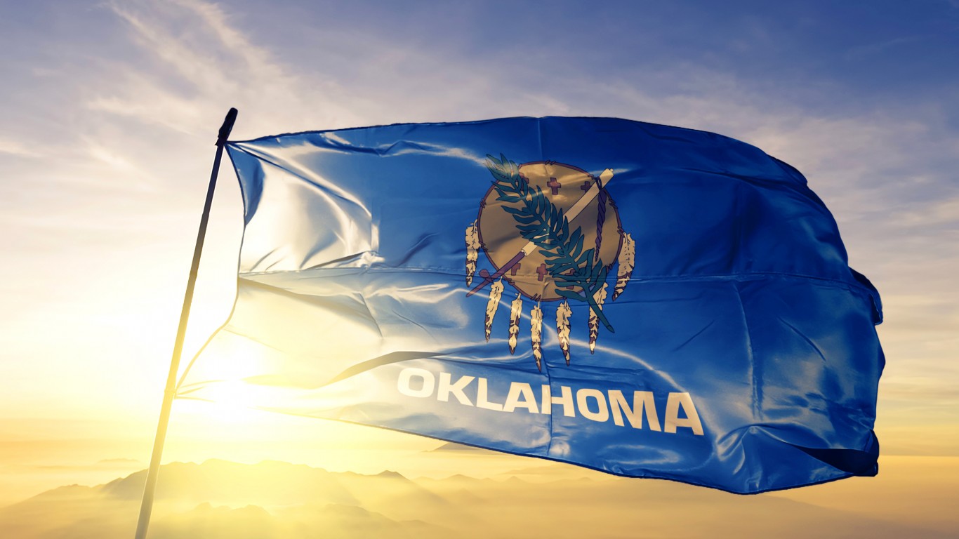 Oklahoma state of United States flag on flagpole textile cloth fabric waving on the top sunrise mist fog