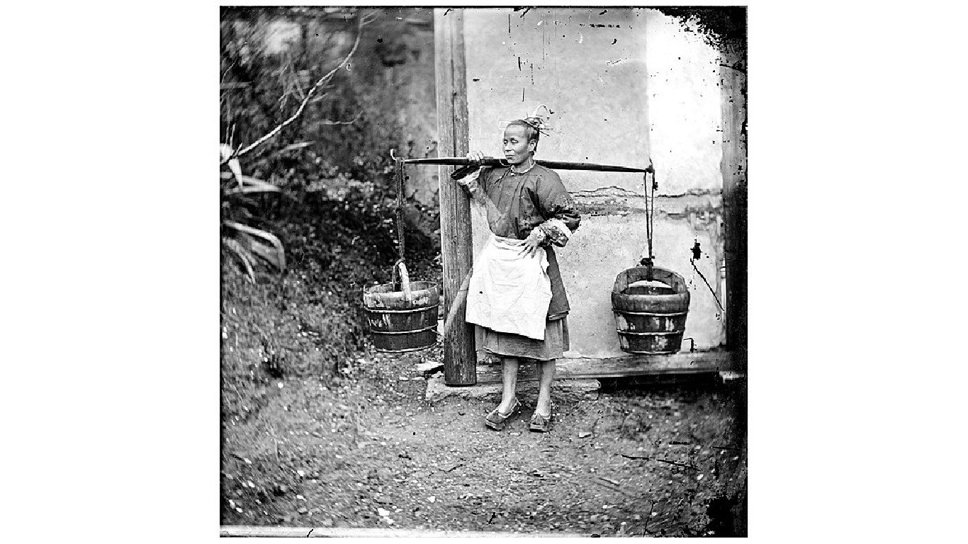 China; a woman carrying buckets of night-soil by John Thomson