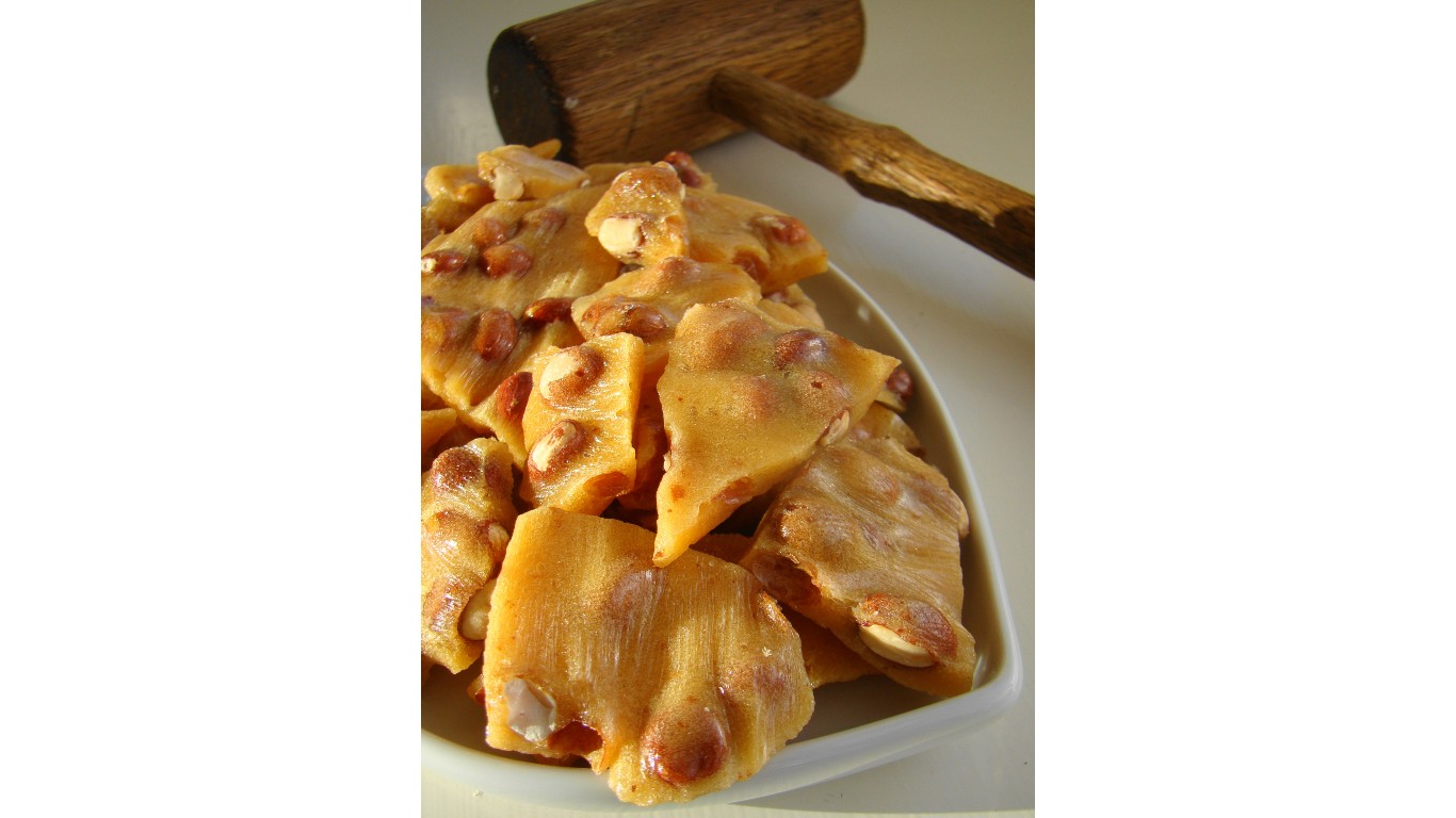 Golden peanut brittle cracked on a serving dish by Janet Hudson