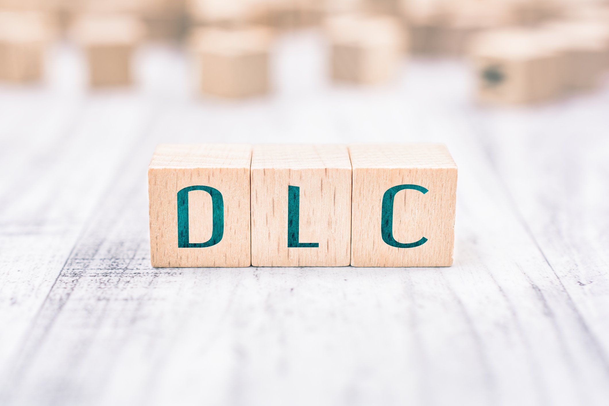The Word DLC Formed By Wooden Blocks On A White Table