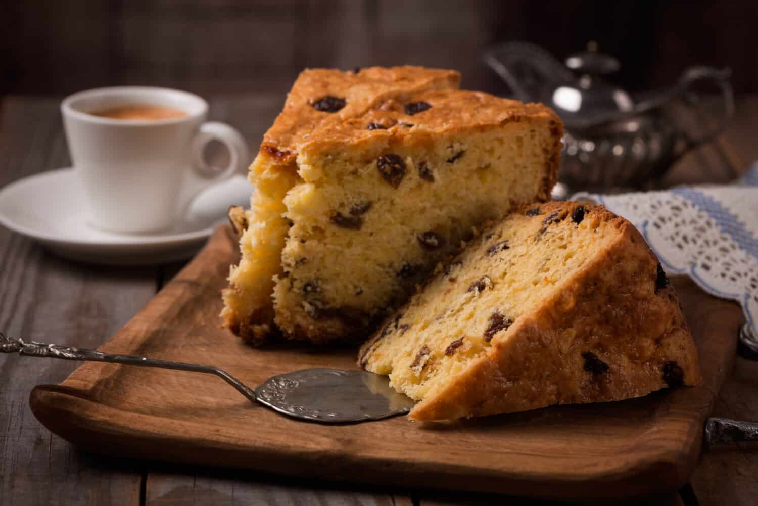 cup of coffee and slices of home made cake with raisins on wooden plate,vintage style