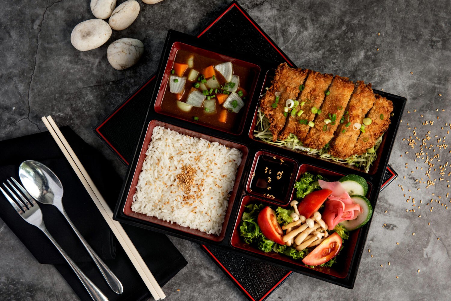 Japanese food bento set with tonkatsu and tempura on dark stone background