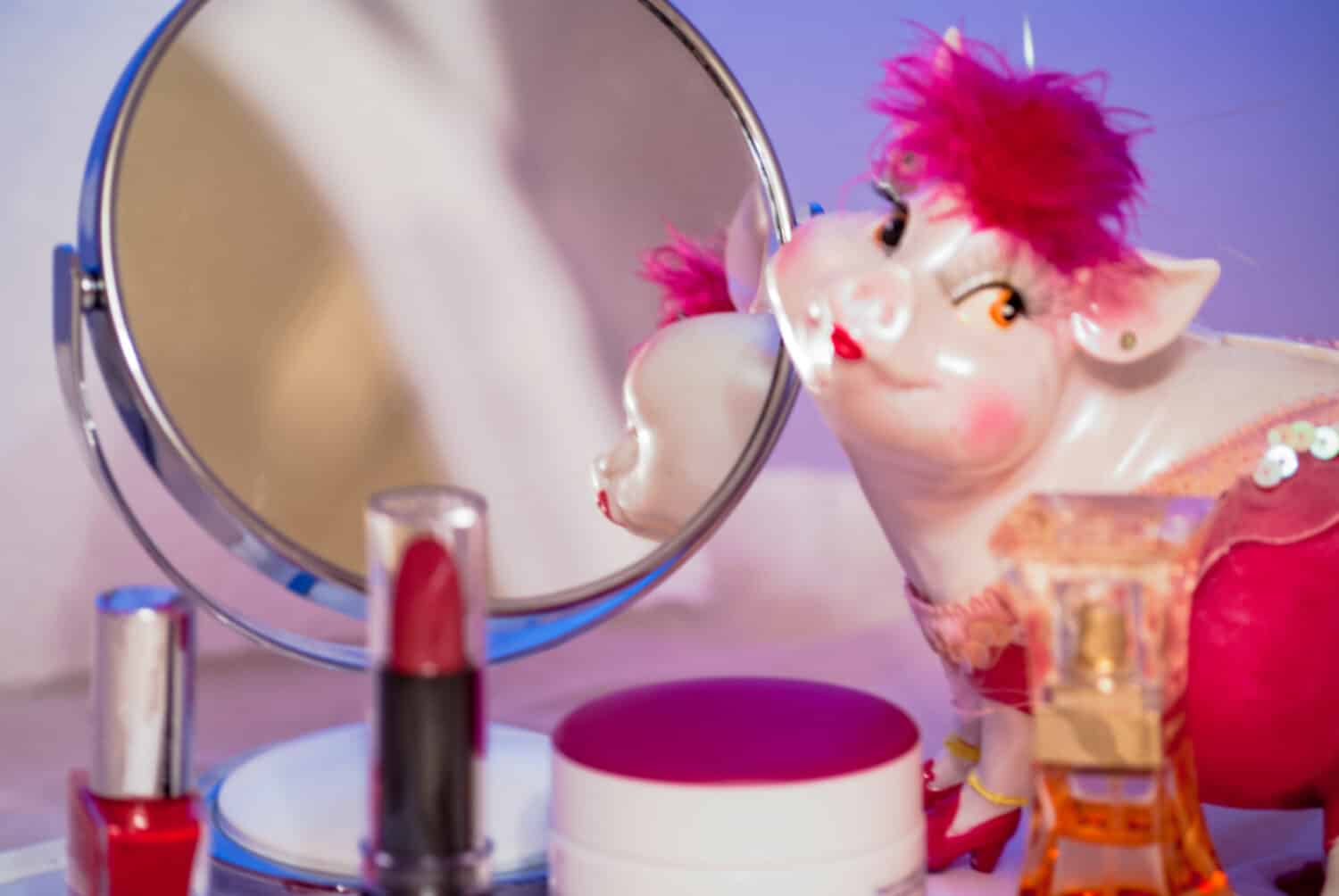 In the mirror desktop look pink piggy toy around her are all sorts of cosmetic things and lipstick red.