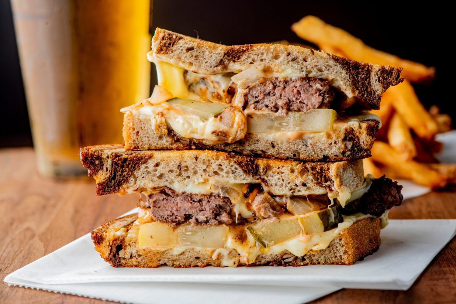 Patty melt sandwich. Ground beef patty with melted cheese and topped with caramelized onions on two slices of griddled rye bread. Classic American meat and cheese Sandwich served with crispy fries.