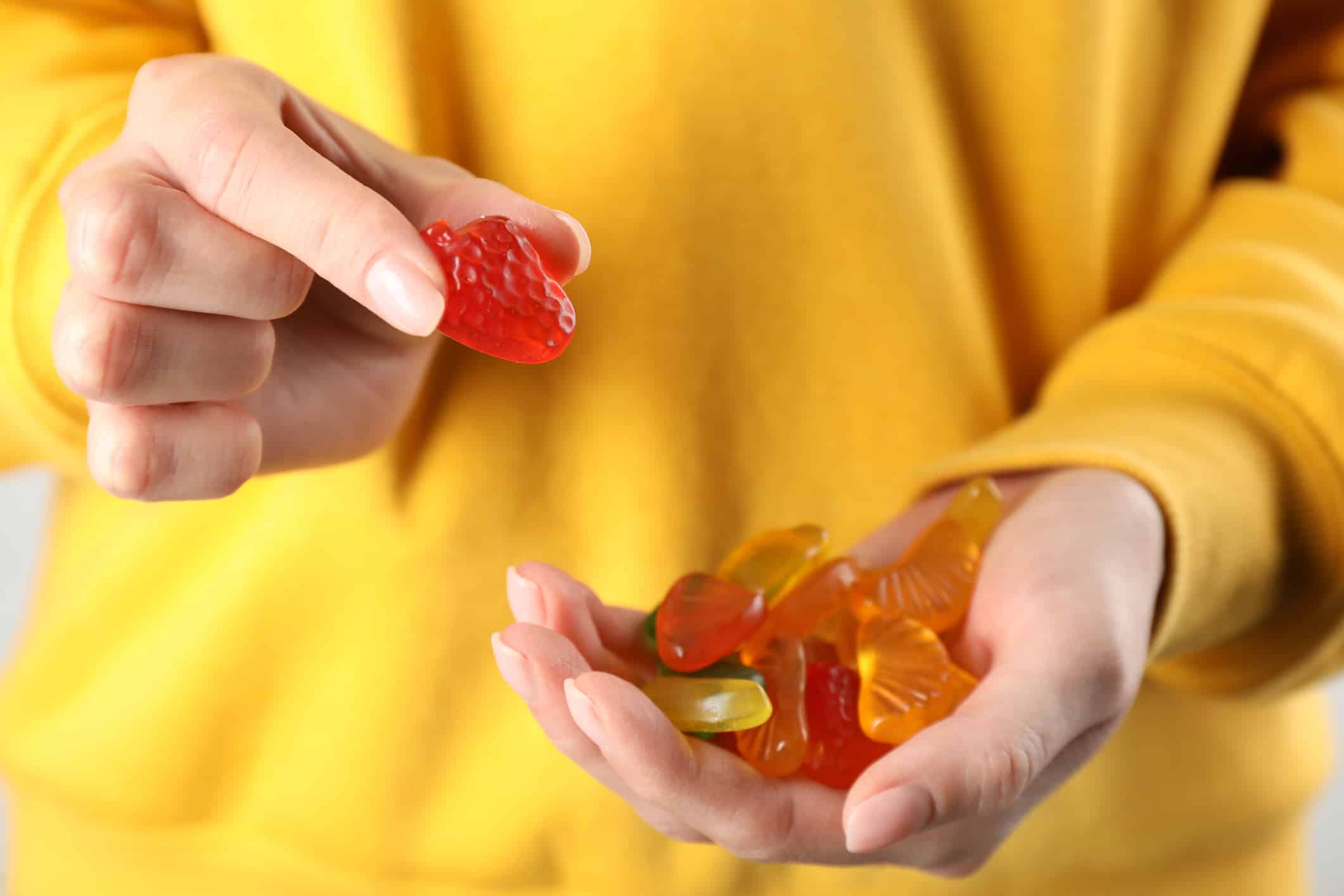Woman holding handful with delicious gummy fruit shaped candies, closeup