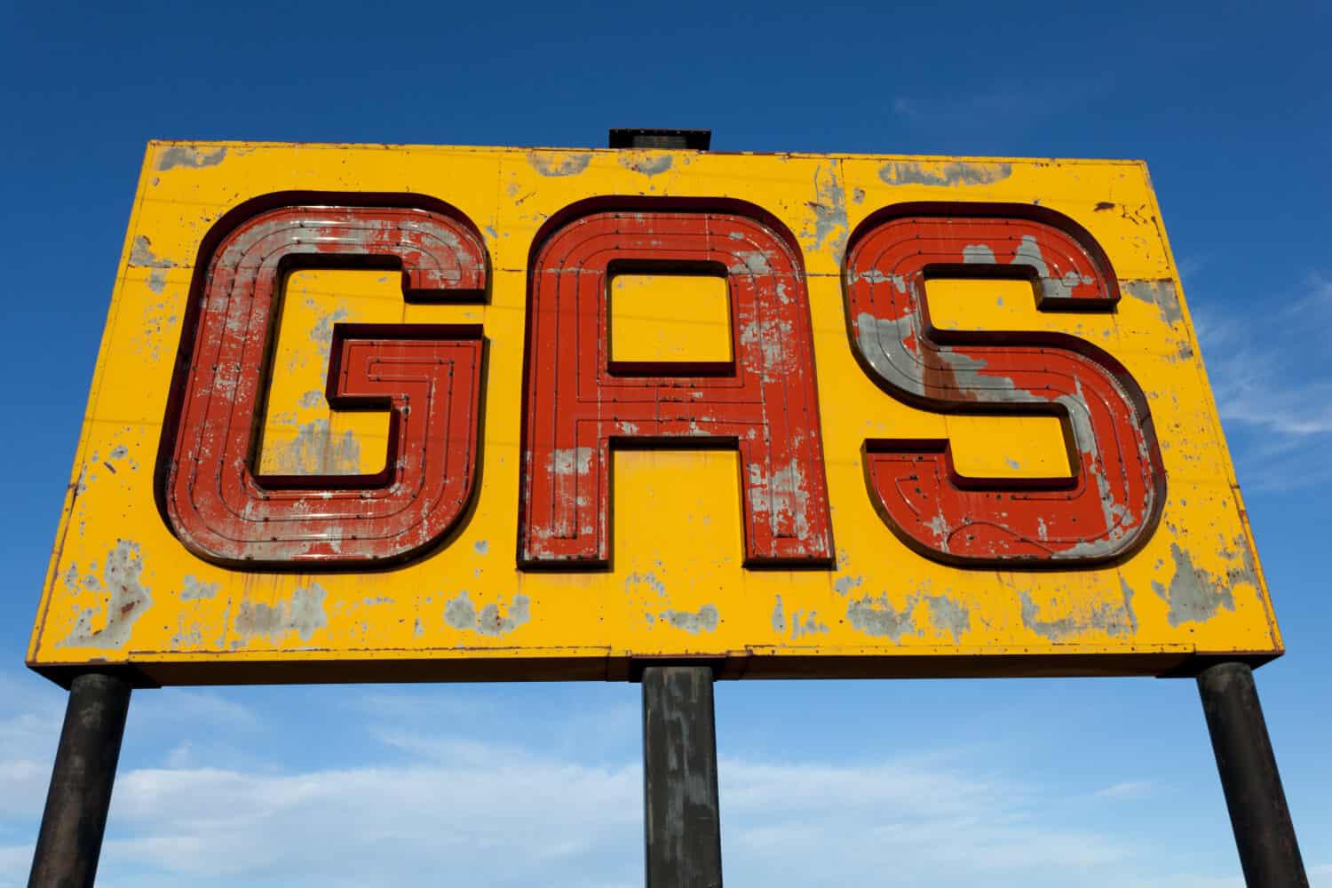 A vintage, antique, gasoline sign in front of a blue sky on a sunny day