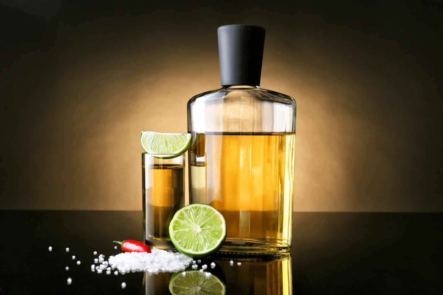 Tasty tequila with lime, salt and chili pepper on dark background