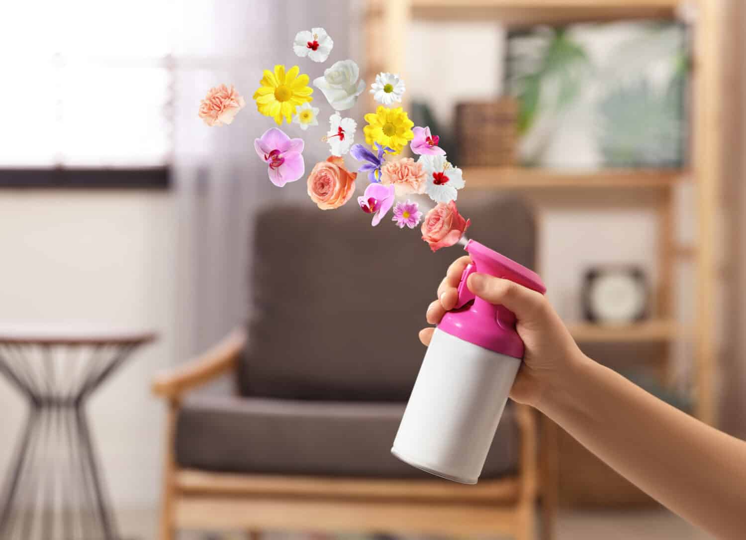 Woman spraying air freshener at home, closeup. Flowered aroma