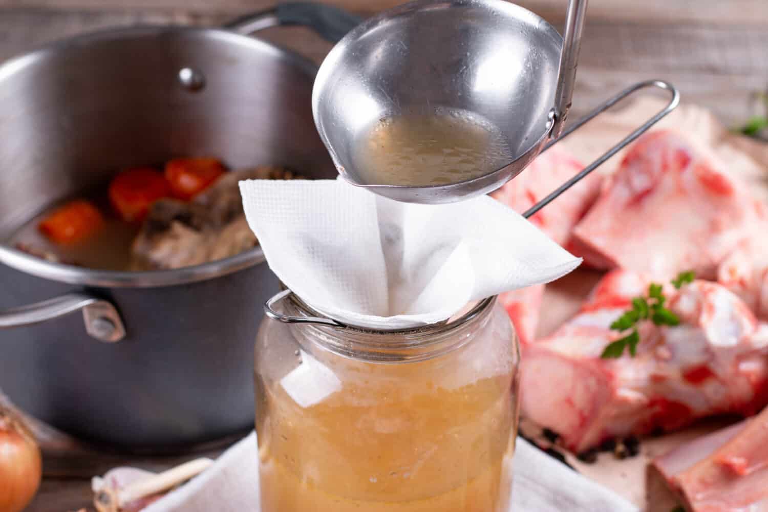 Passing the bone broth through a sieve and through a paper napkin. Concentrated Bone Broth in a Glass Jar