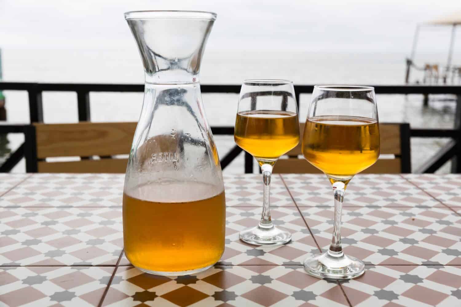 Orange wine from Kvevri. Batumi, Tbilisi restaurant on the seashore. A pitcher and two glasses. Against the background of the sea
