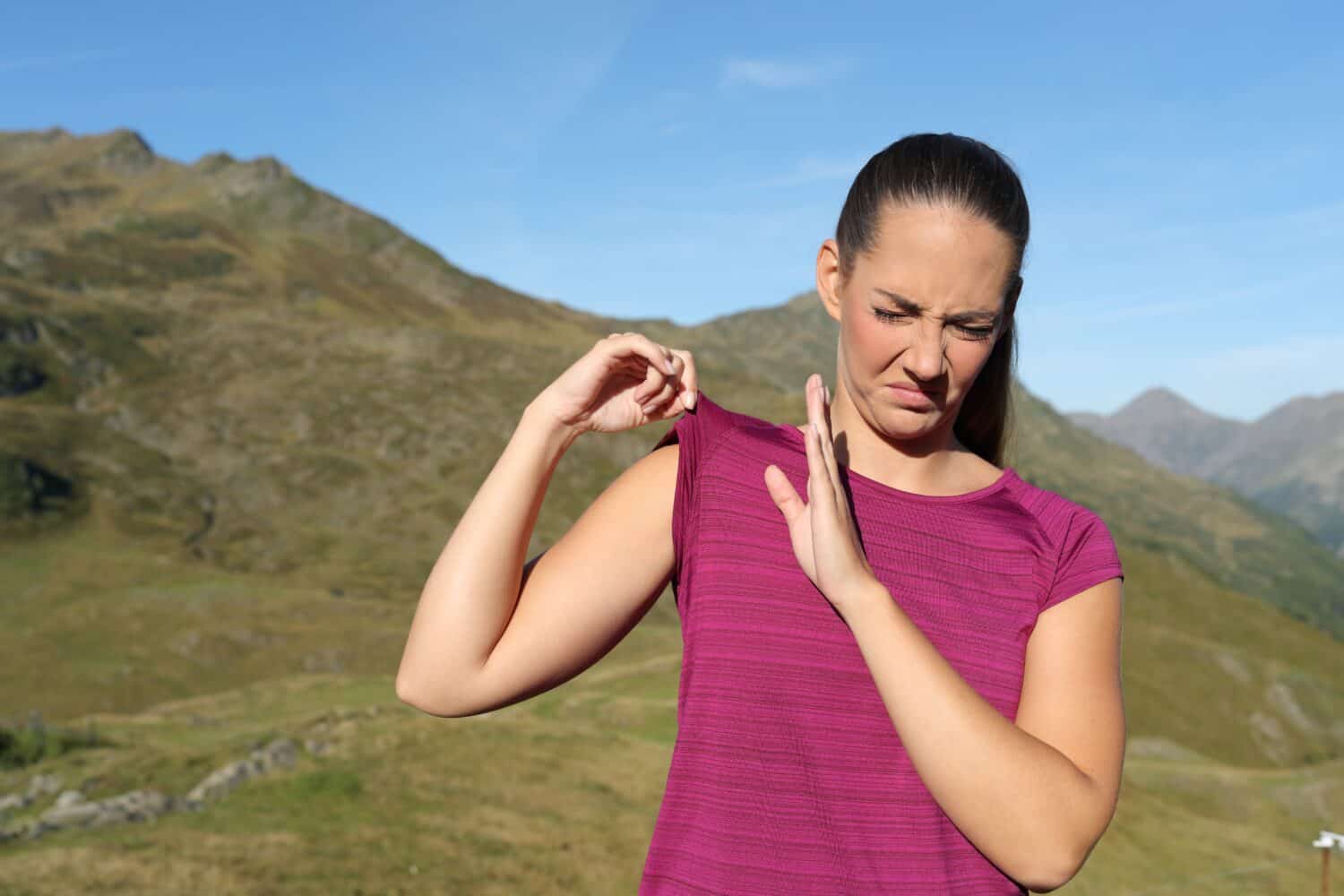 Sportswoman smelling stinky clothes after sport in nature
