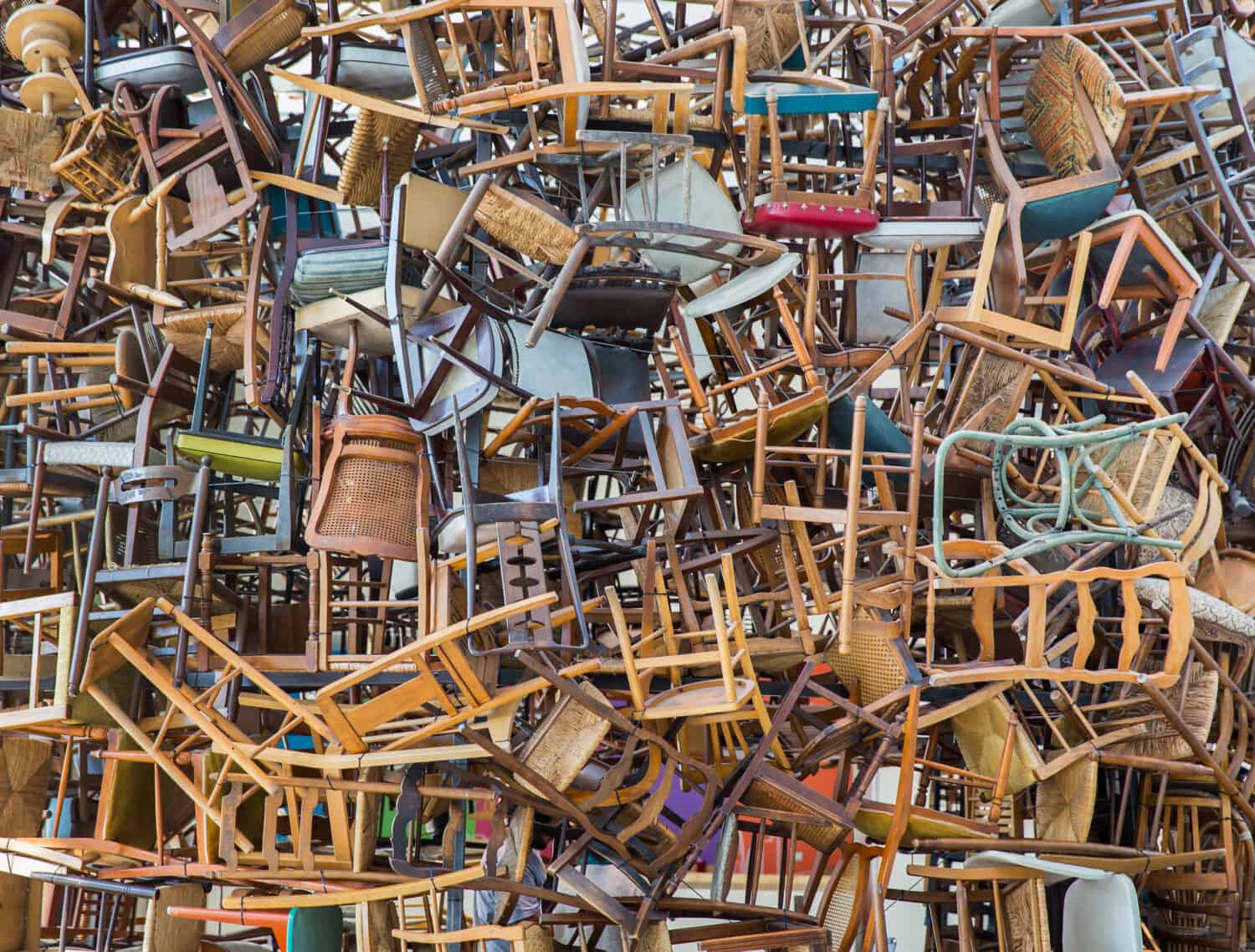 Stack of assorted metal and wooden chairs in random disarray, full frame furniture background image