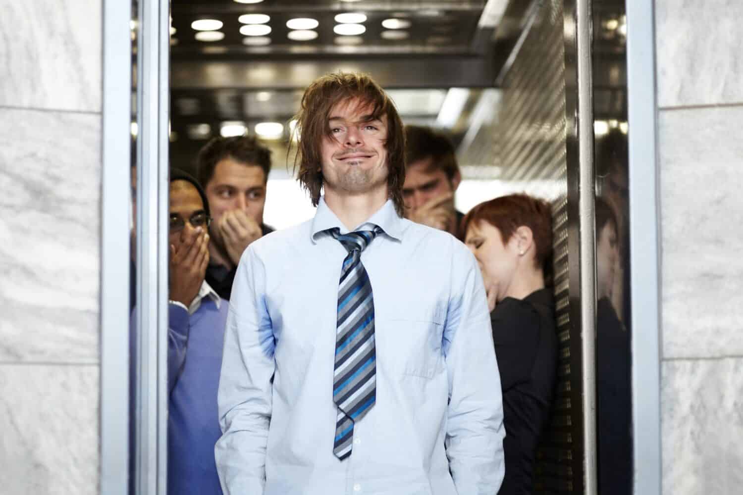 He needs a shower. A dirty young businessman affecting his coworkers in an elevator.
