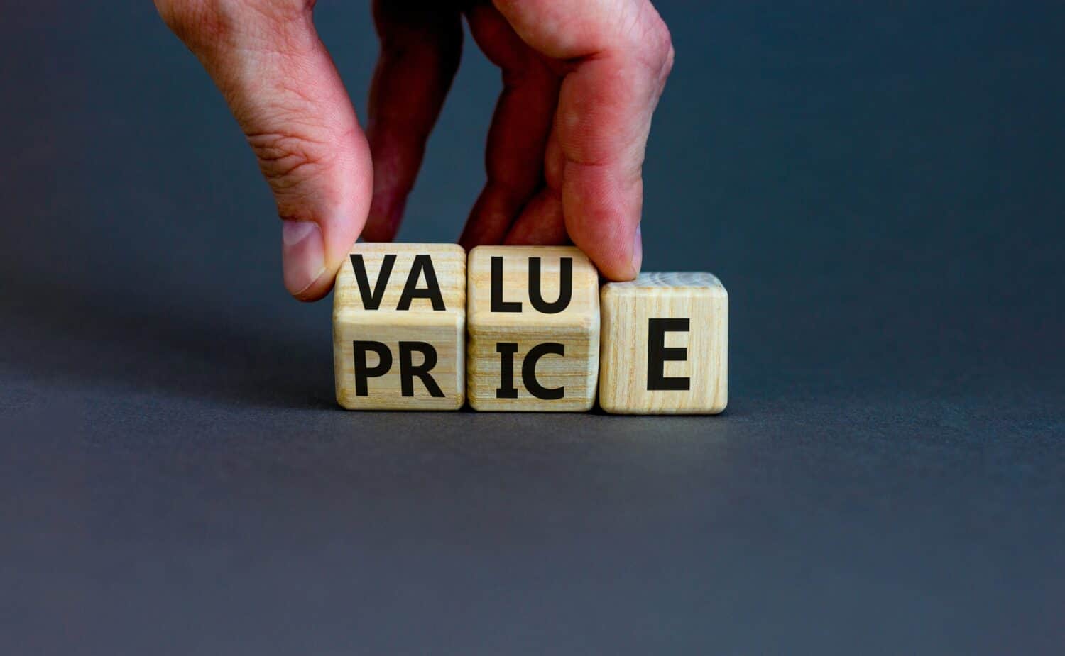 Businessman turns wooden cubes and changes the word price to value or vice versa. 
