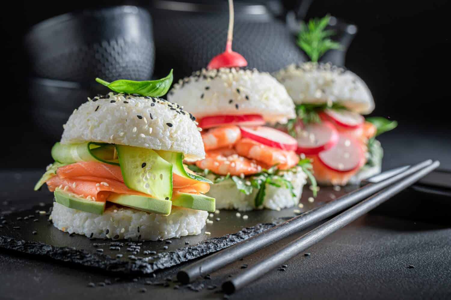 Unique and delicious sushi burger with seafood and rice on strone plate. Japanese dessert made of seafood and rice.
