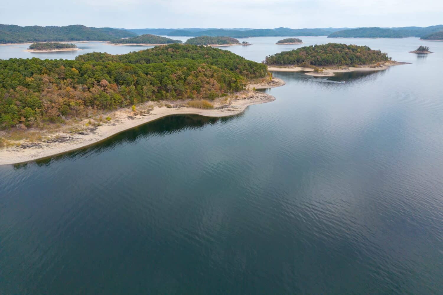 Aerial view of landscape of water of Broken Bow lake and islands with forest on the bank, Oklahoma, USA. Autumn scenery of coastal line.