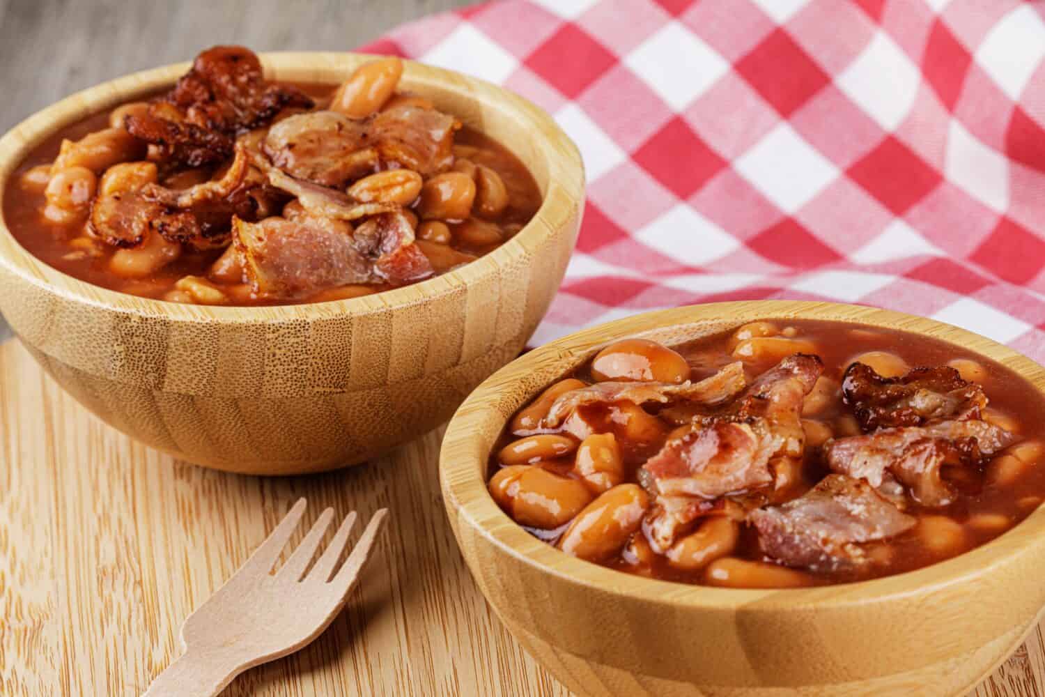 A wooden bowl of Baked Beans also known as Pork Beans on a wooden background with copy space
