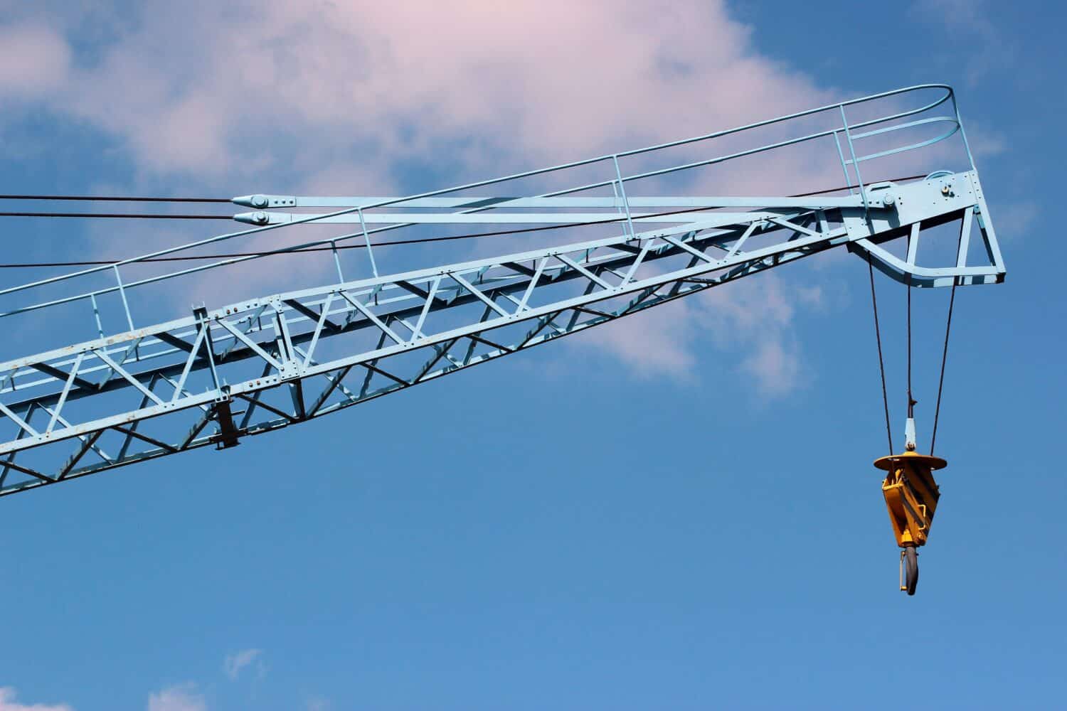 Construction crane arm with hook against blue sky background