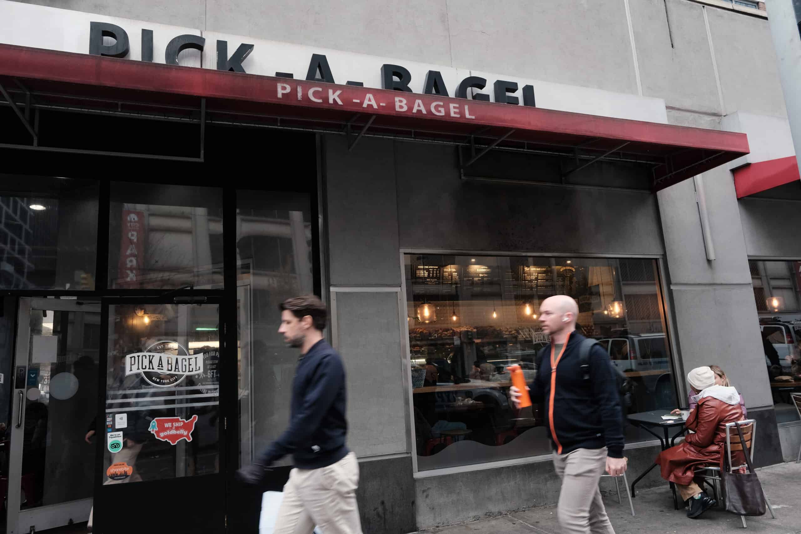 People walking by a Pick-a-Bagel, a bagel shop in Manhattan 