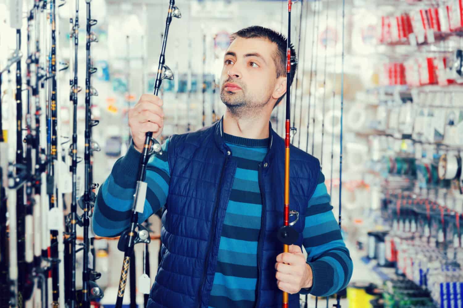 Man shopper choosing ocean fishing rod in the fishing store