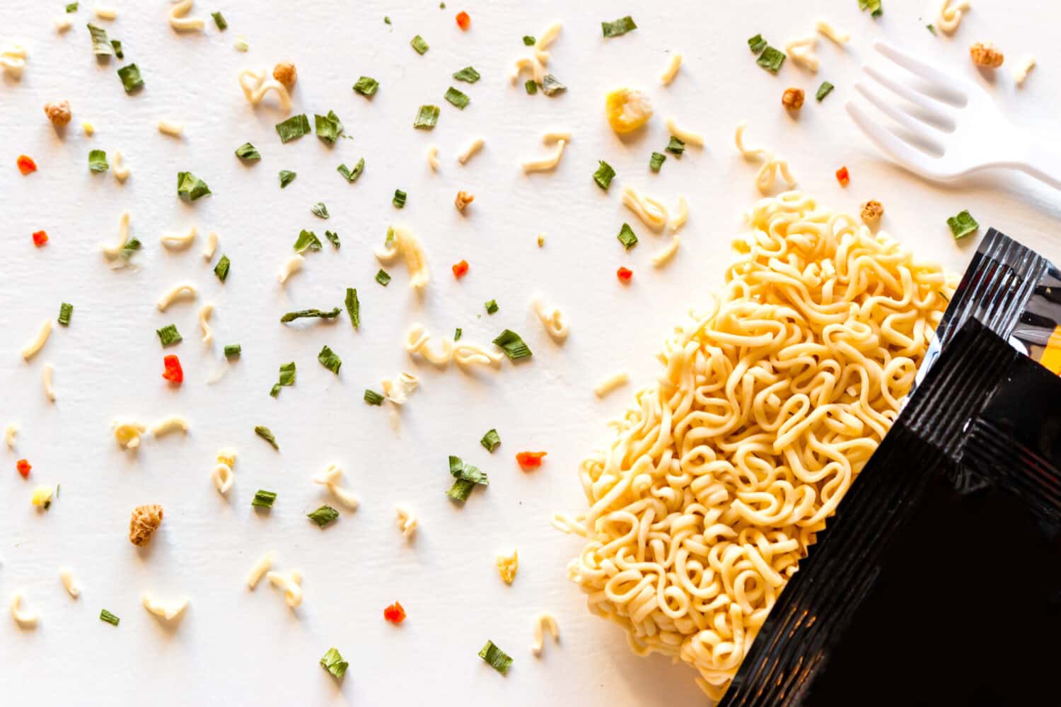 packaged instant noodles with spices on a white background