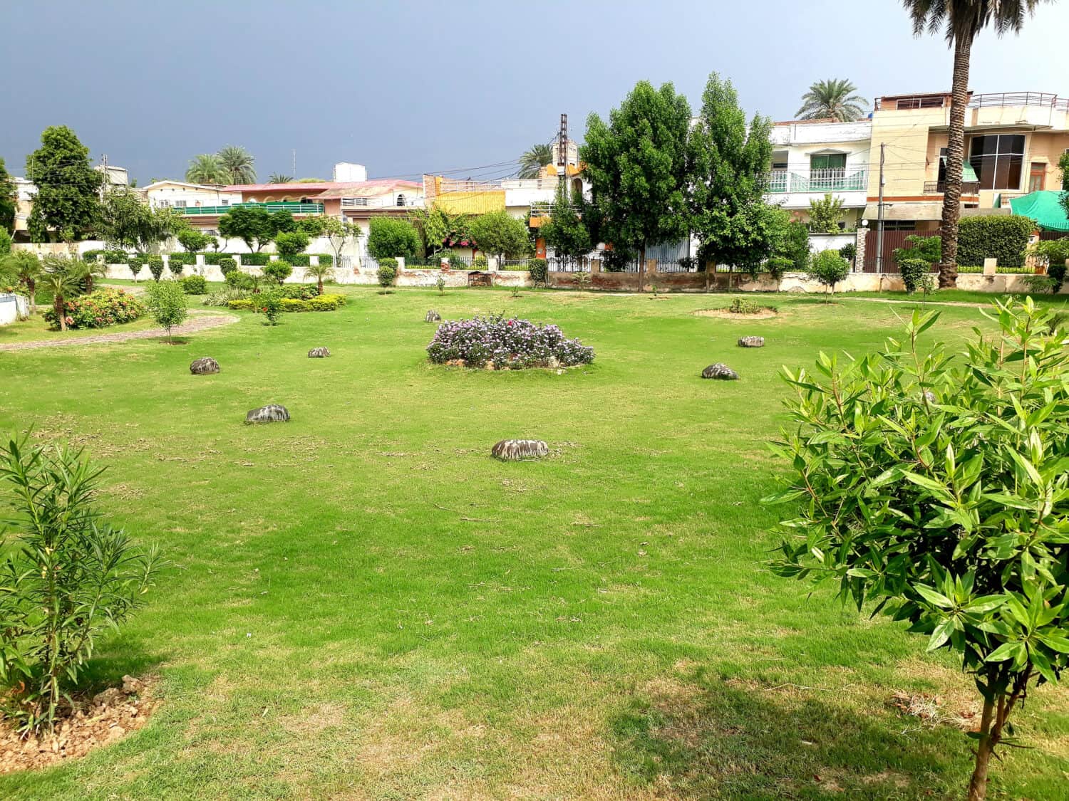 Beautifull Landscaped park in sargodha with beautifull flowers grass plants trees sky and gravells also walking tracks