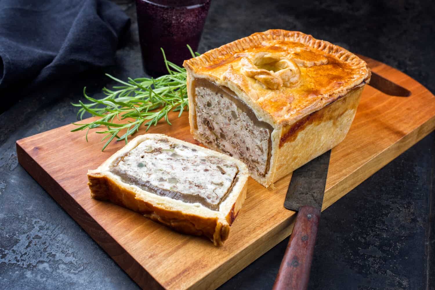 Traditional French Pate en croute with chicken offered as closeup on a modern design cutting board