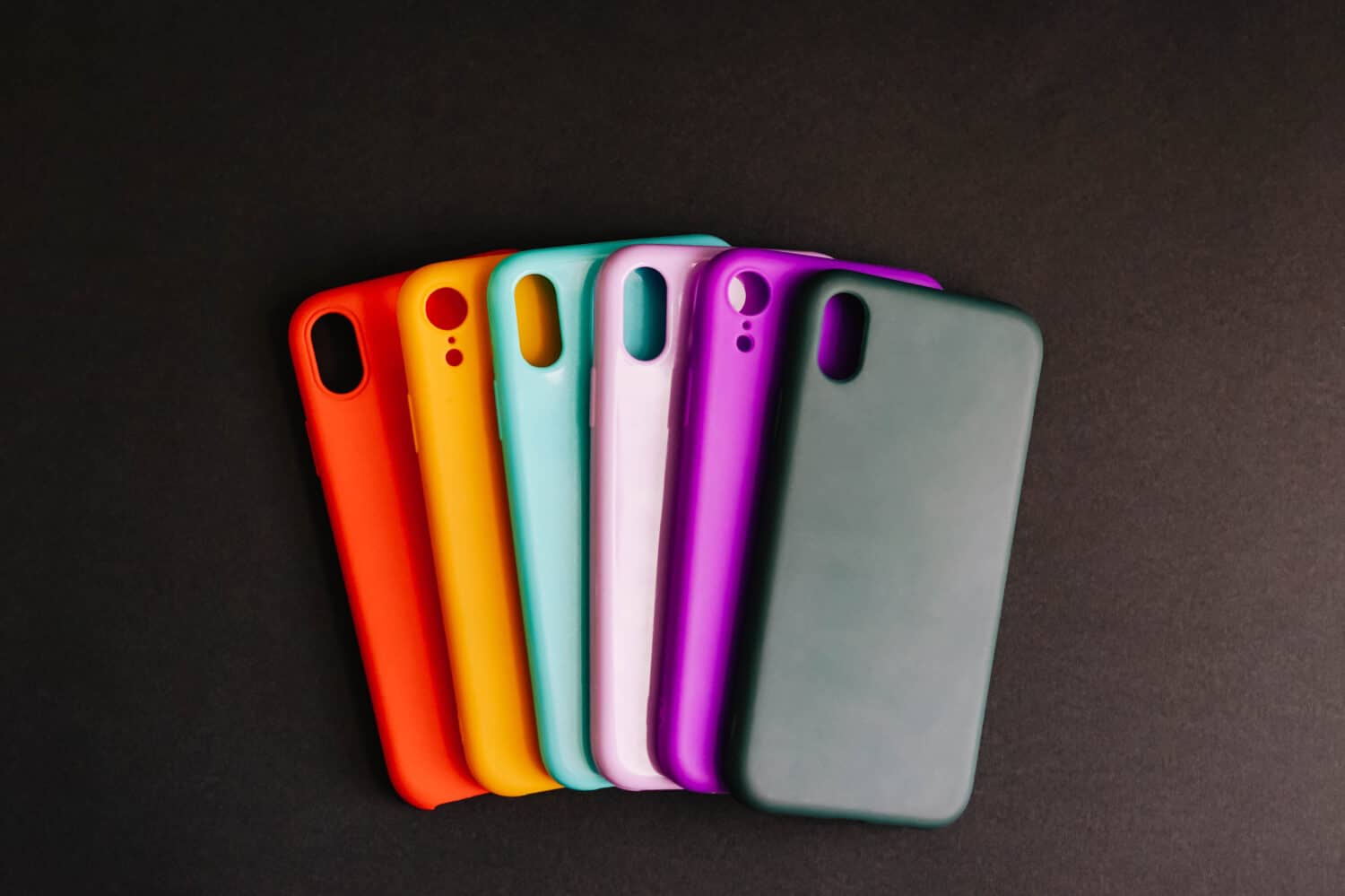 Yellow, red, purple, lilac, green, mint cases for the smartphone on the black background. Protective silicone cases for smartphone. Colorful silicone cases for your smartphone. Selective focus.