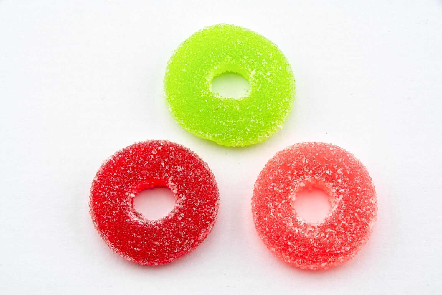 Three round sugar coated gummi sweets on a white background