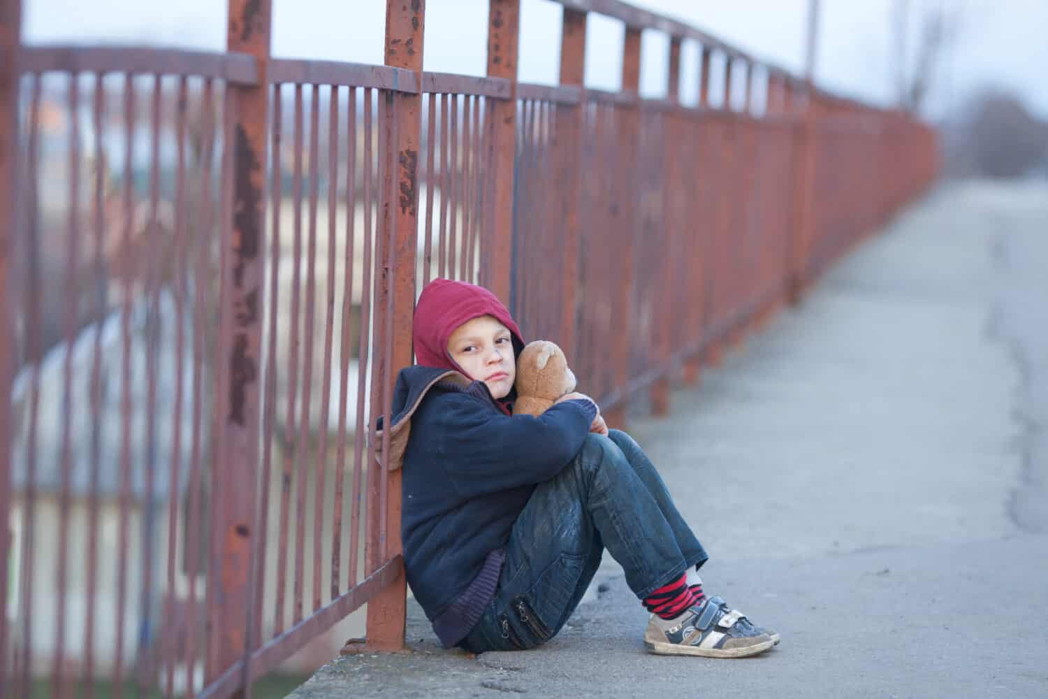 homeless young boy sitting on the bridge