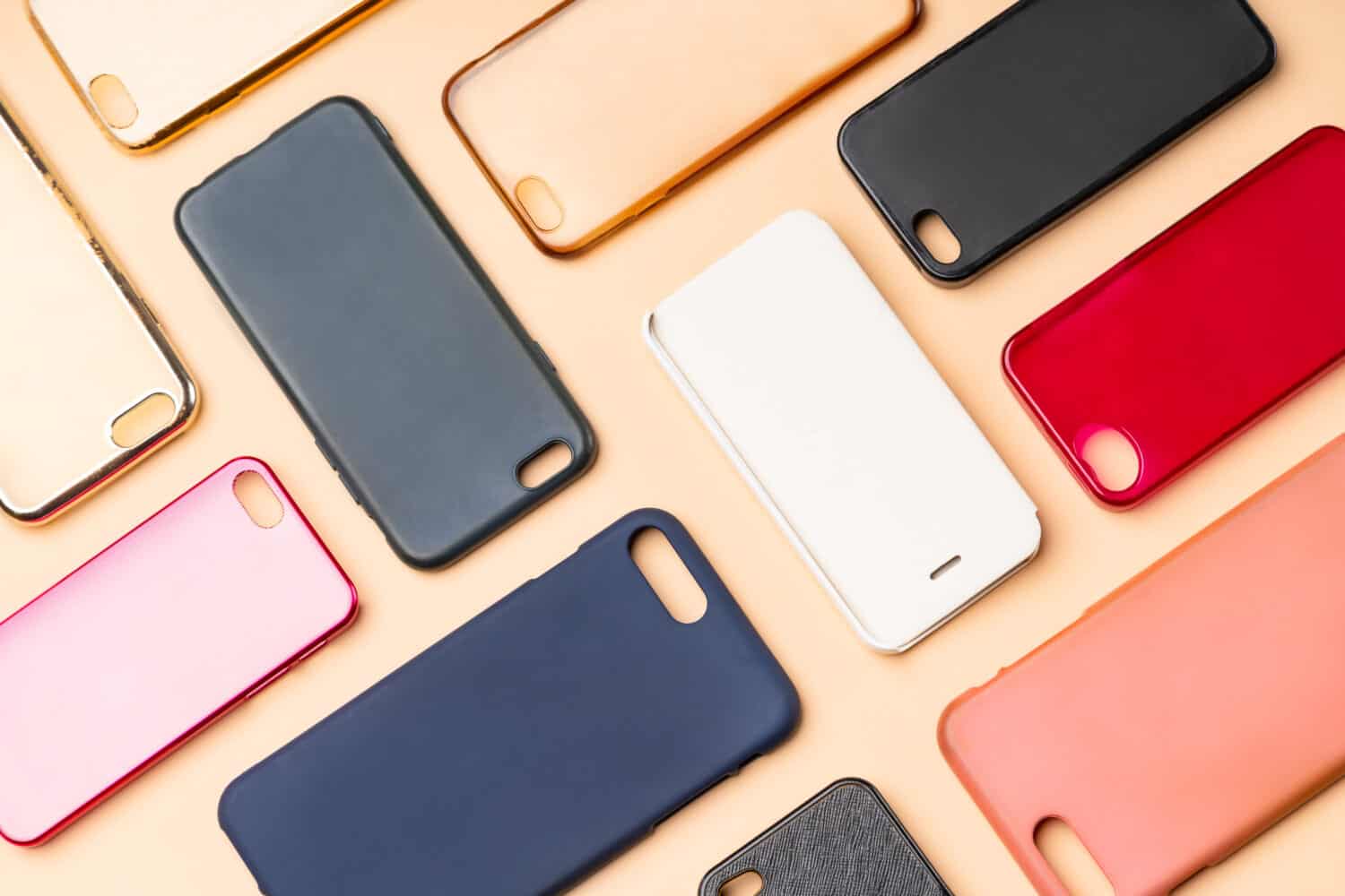 Pile of multicolored plastic back covers for mobile phone. Choice of smart phone protector accessories on neutral background. A lot of silicone phone backs or skins next to each other