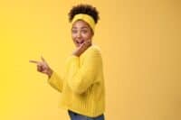 Profile studio shot amused impressed speechless cute stylish shopping girl drop jaw amazed widen eyes turning camera surprised cover open mouth palm pointing left index finger show cool promo