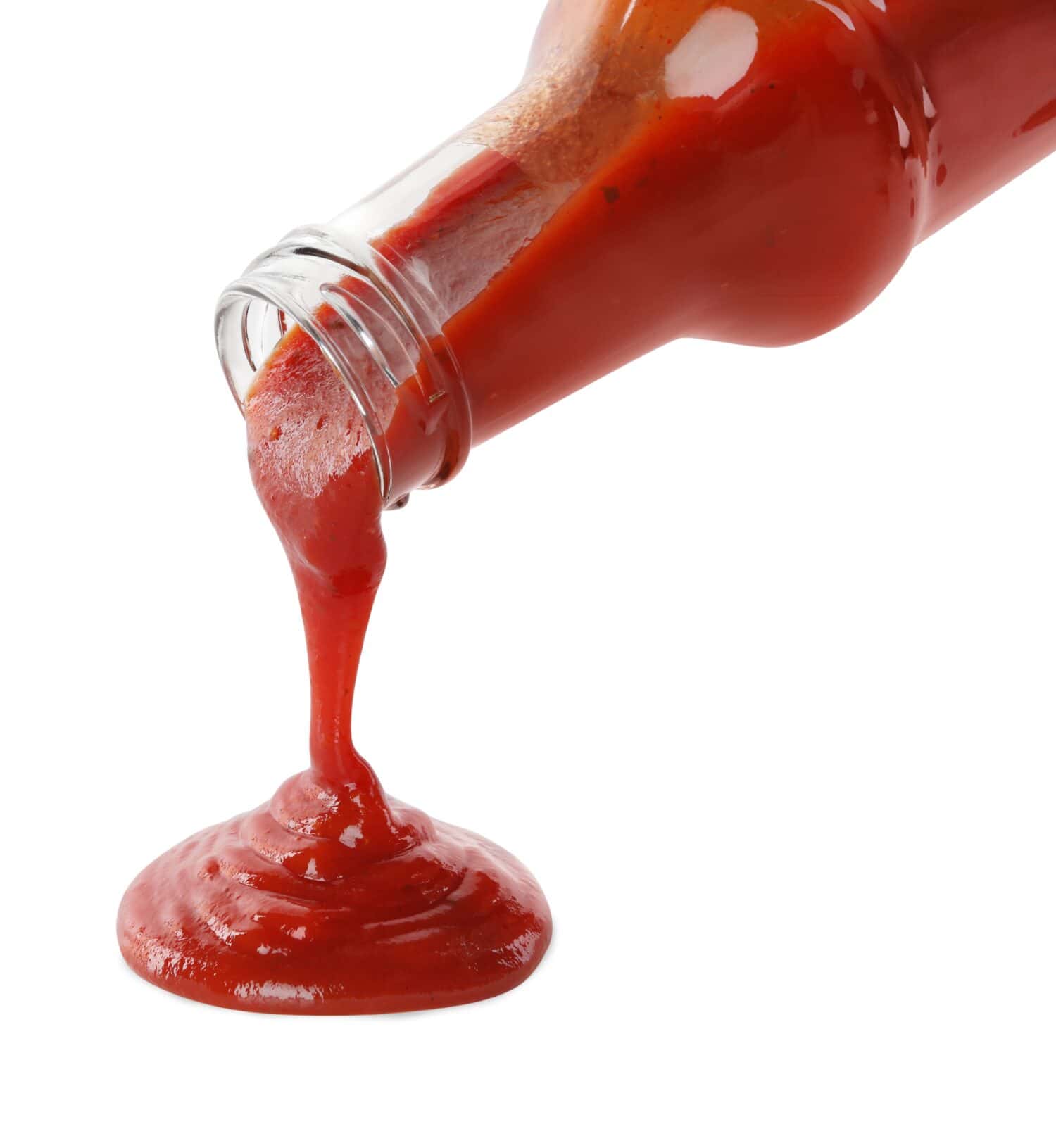 Pouring tasty ketchup from glass bottle on white background, closeup