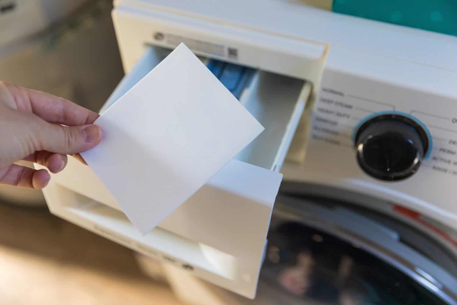 A woman putting a laundry sheet in a washing machine