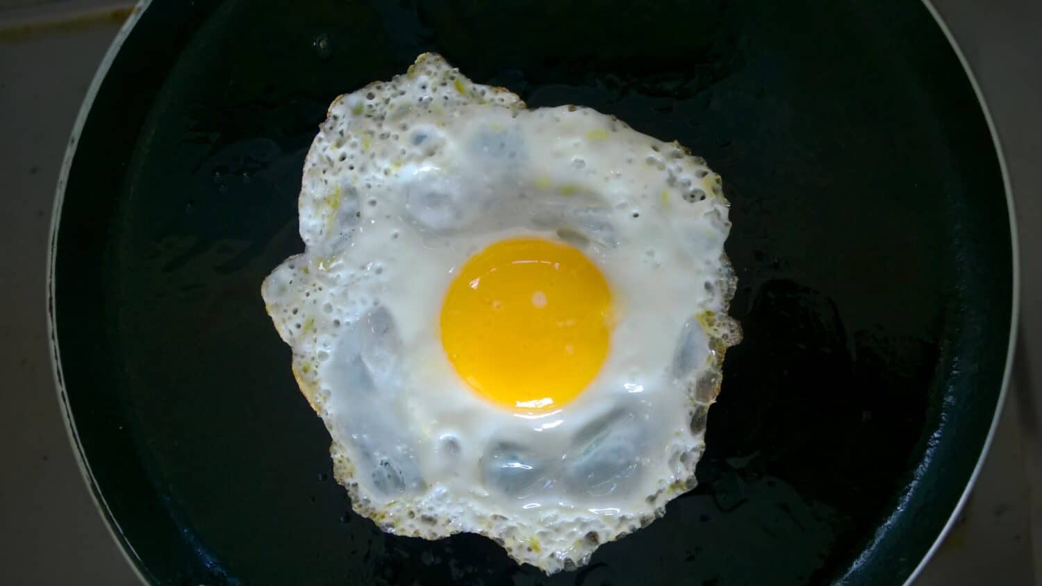 Sunny side up poached egg or omelette on a skillet or pan. Top view.