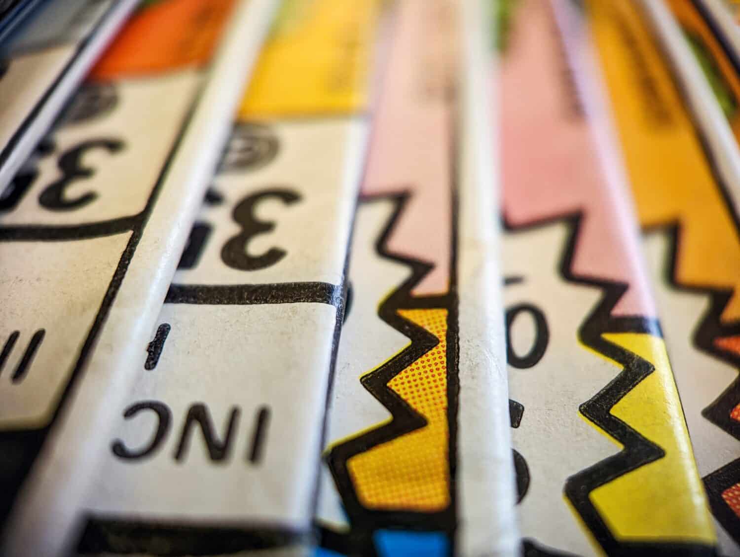 Closeup view of an old comic book collection stacked in a pile creates a colorful background paper texture with abstract shapes