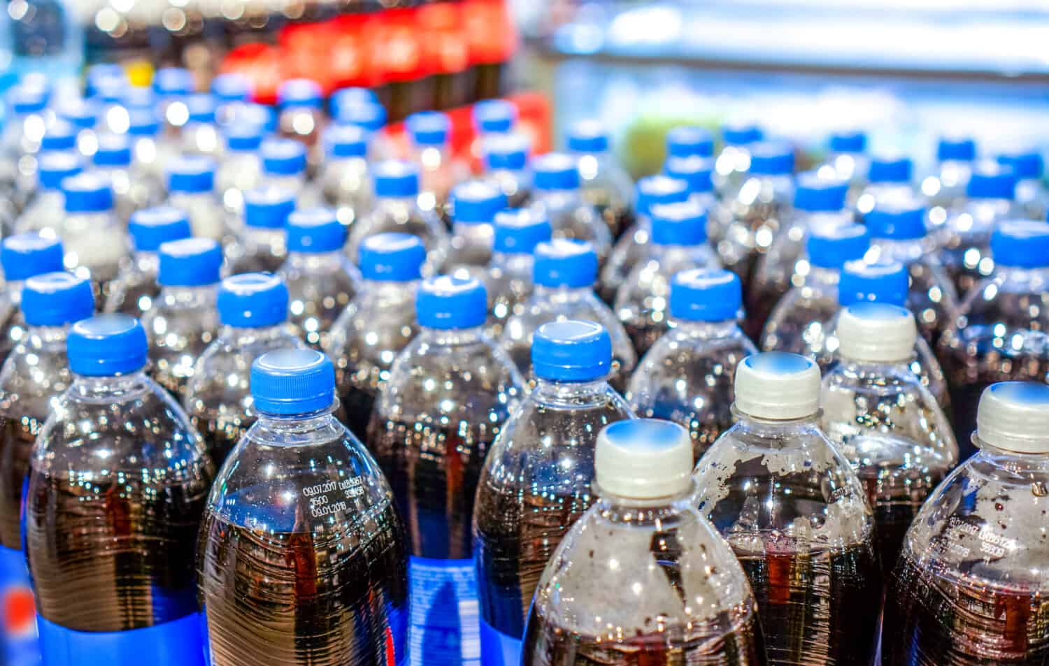 the army of plastic bottles of black liquid with navy blue caps stand in strong lines at the store waiting for buyers. Many top view pepsi bottles. background made of big pepsi bottles