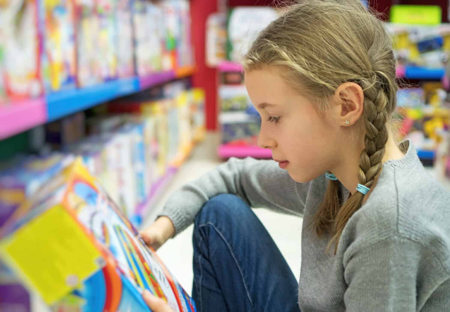Little girl selecting toy in kids store.
