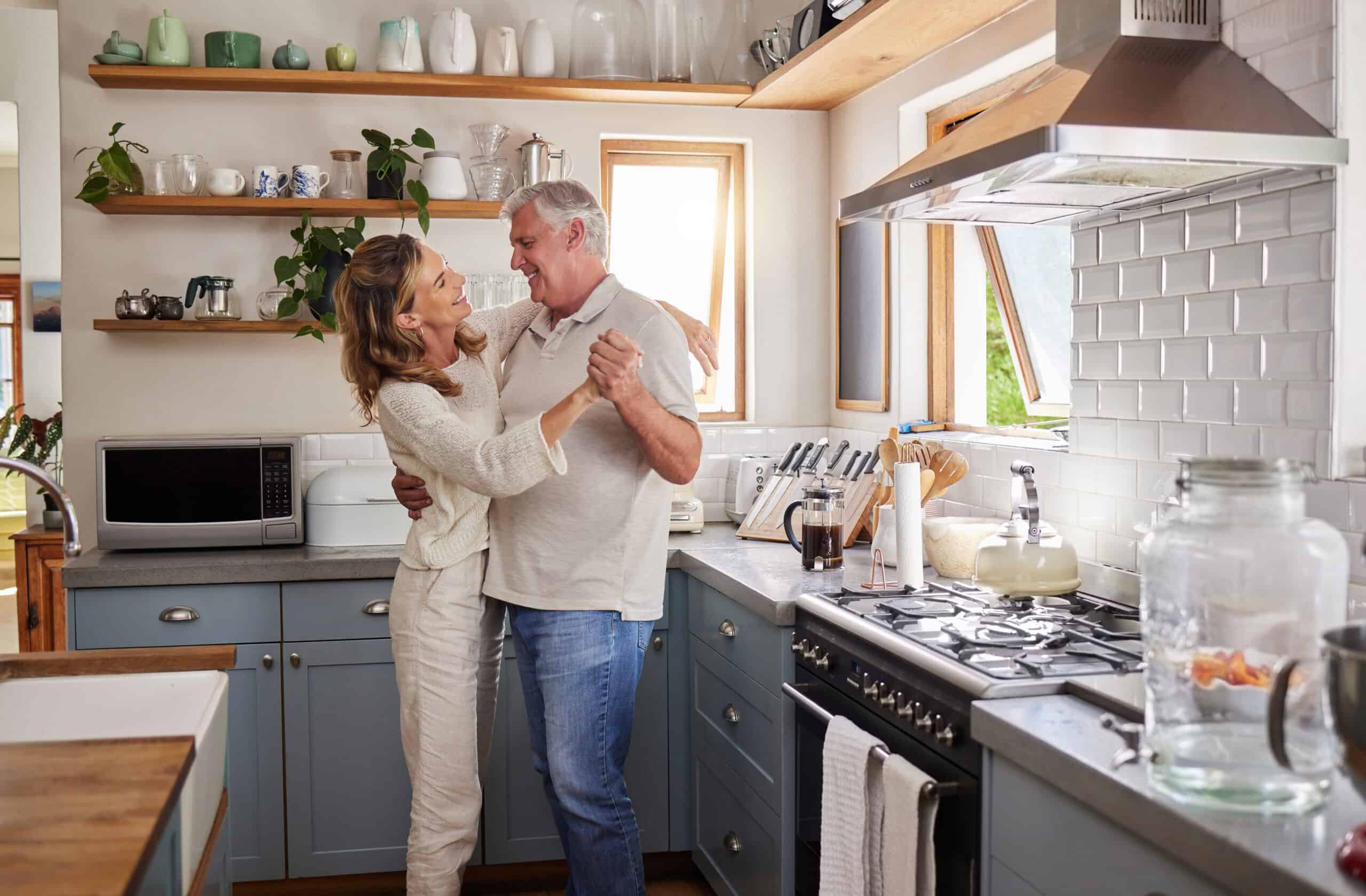 Couple, dance and kitchen with a senior woman and man dancing while happy together in their home. Retirement, smile and love with elderly pensioners being romantic in a house in the morning