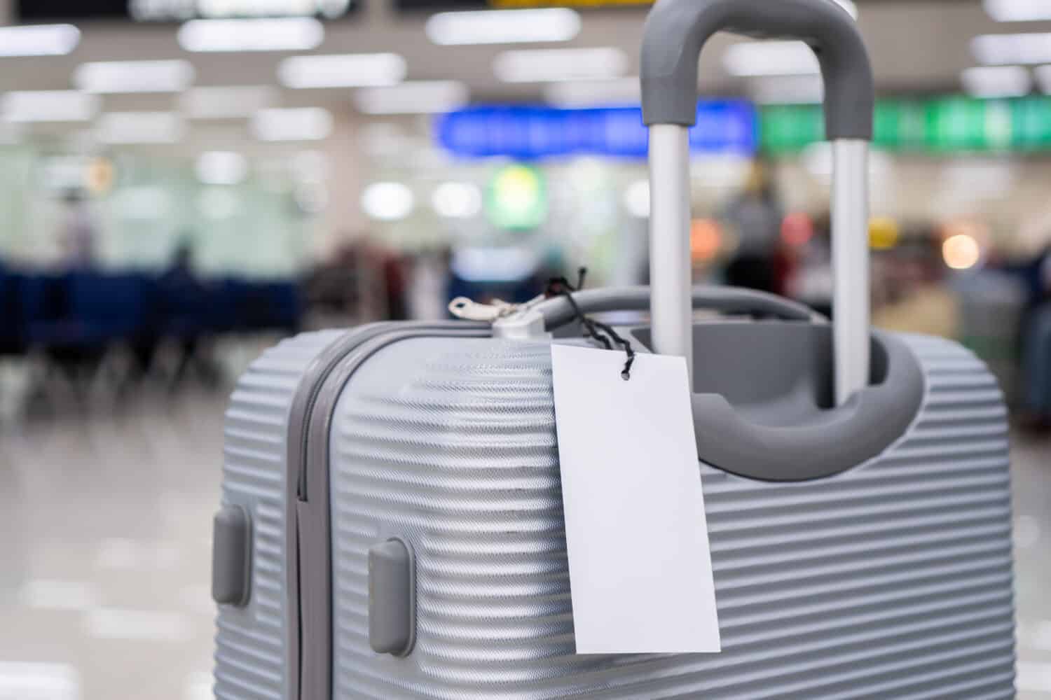 Luggage holder tag blank label on suitcase / baggage put letter "Travel insurance" word for display your products near combination locks for traveling luggages in airport terminal, copy space for text