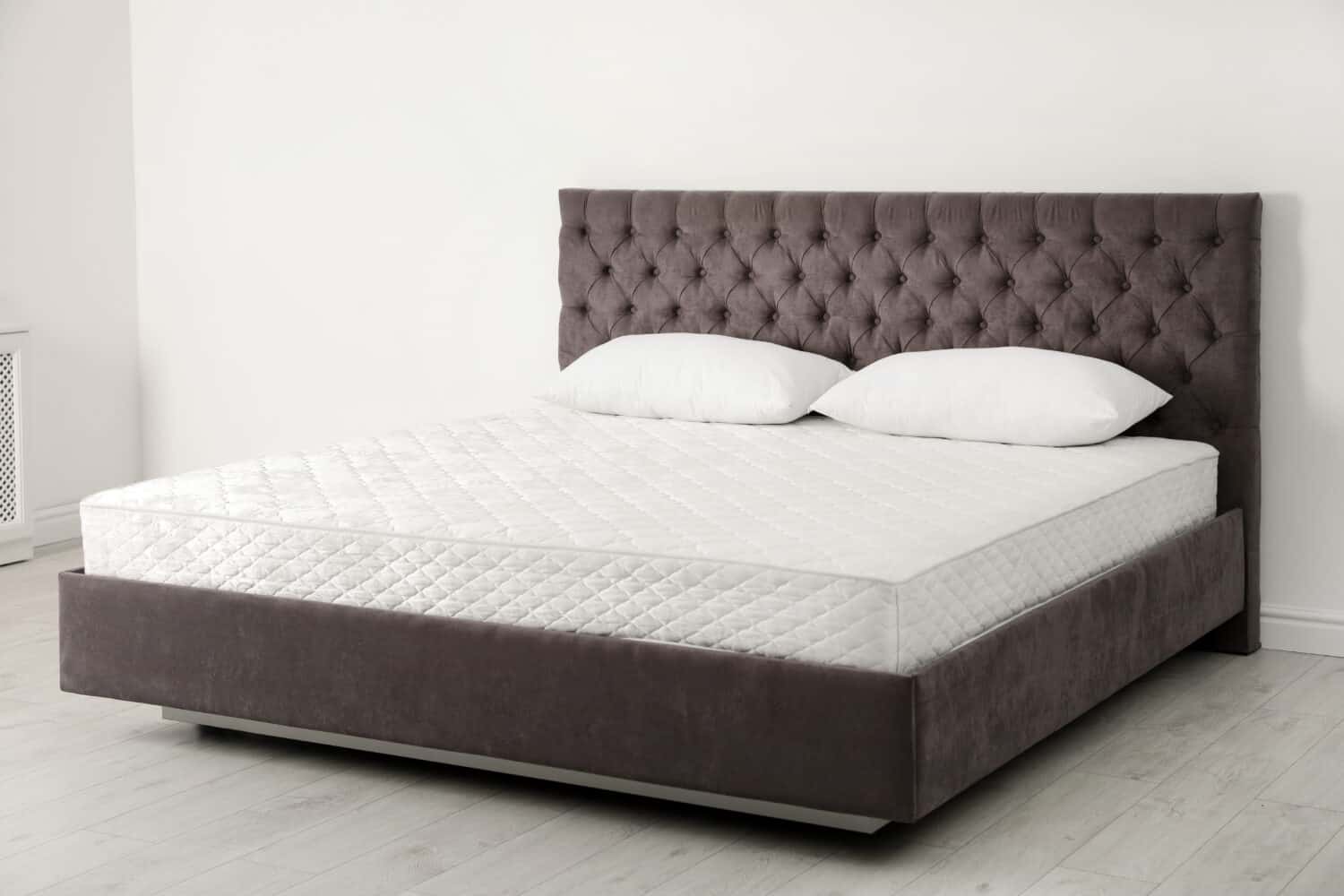 Comfortable bed with new mattress near wall in room. Healthy sleep