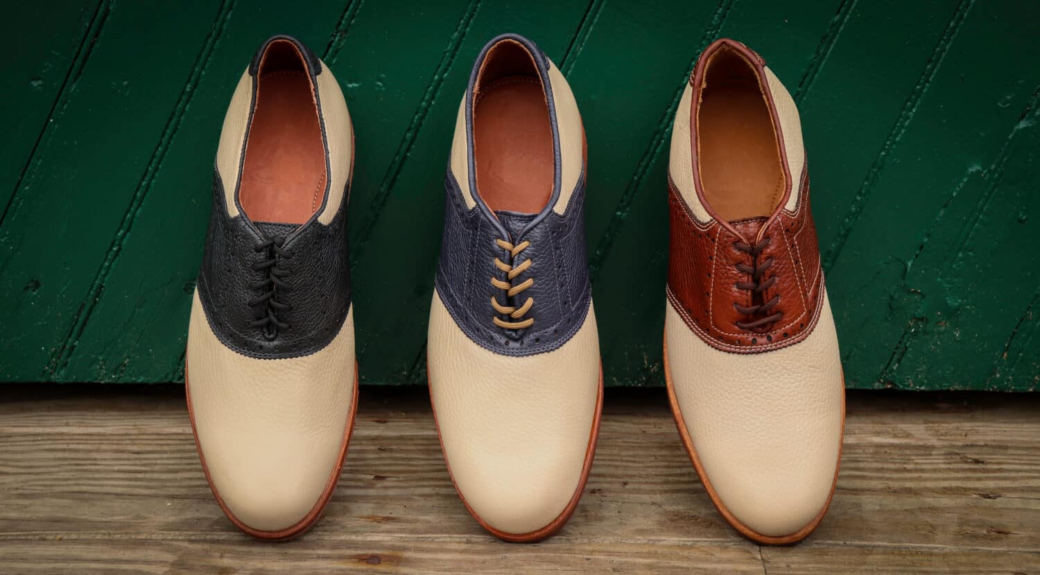 Men's saddle shoes against a wooden doorway outside, with a vintage rustic theme.