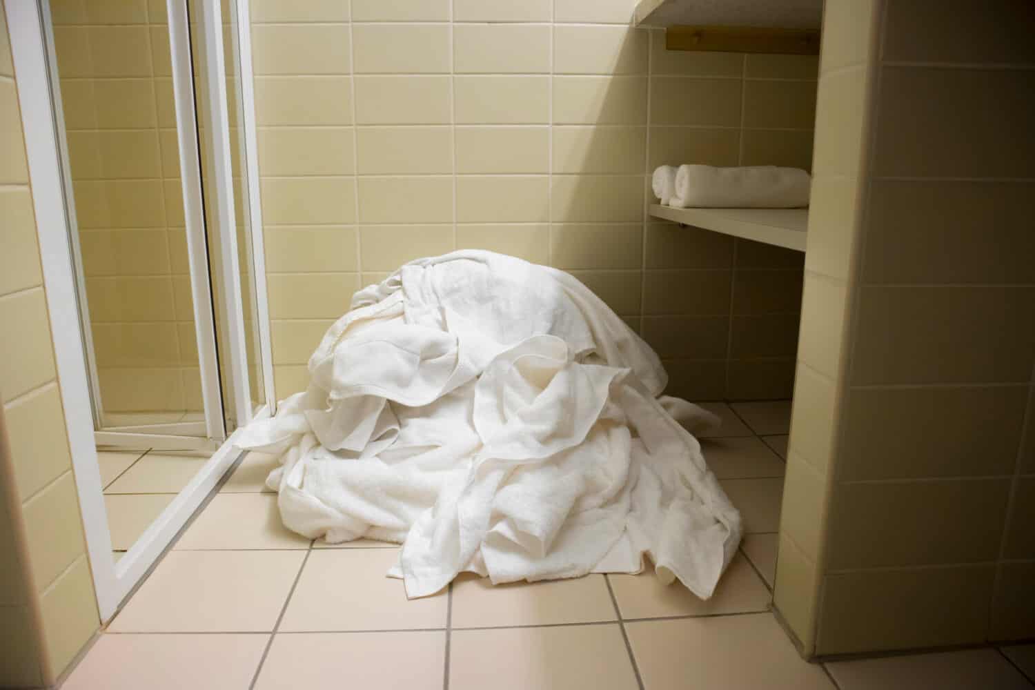 Pile of dirty used towels on the hotel bathroom floor. Housekeeping replace only the used towels on floor with clean ones. Saving water, soap, energy as a green policy.