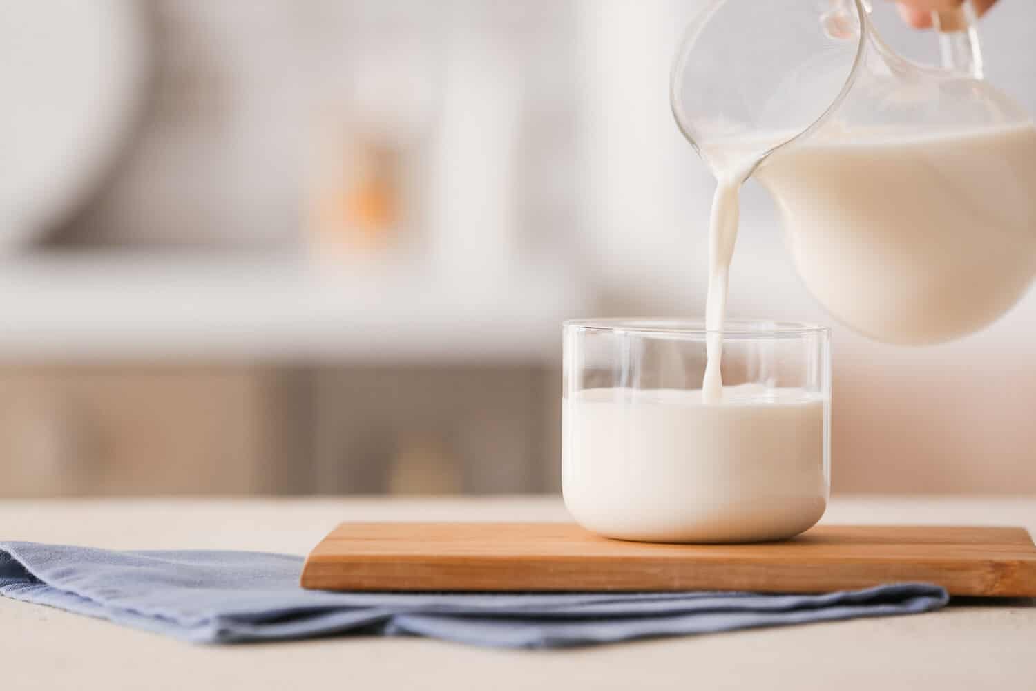 Pouring of milk into glass on table