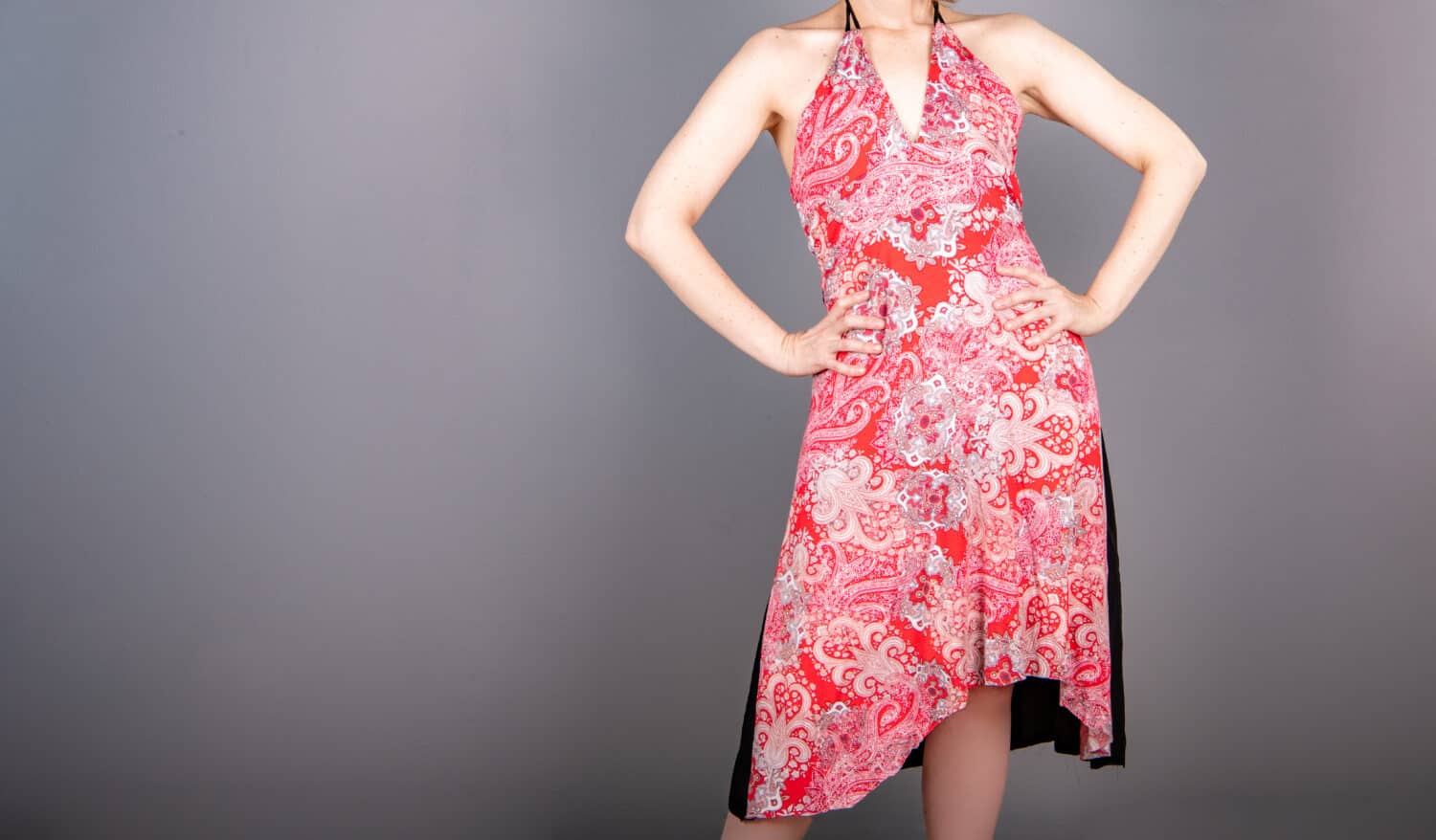 Half length view of a model posing in a red print dress with a halter top. Hand sewn dress. Fashion design.